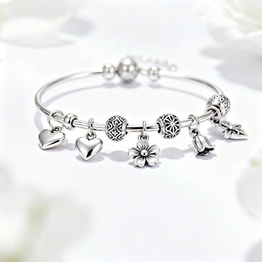 Elegant silver charm bracelet with heart, flower, and bell charms