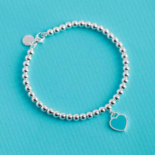 Silver heart tag bracelet with turquoise enamel charm on beaded chain, elegant accessory for gifting or daily fashion.