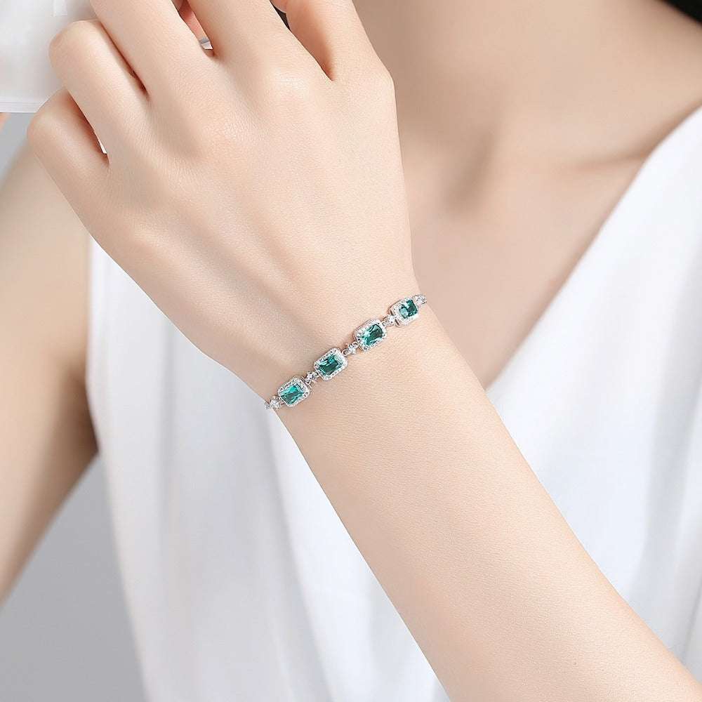 Model wearing Emerald Bracelet - Baguette Cut Emerald showcasing its elegant design and vibrant green stones on wrist for fashion inspiration.