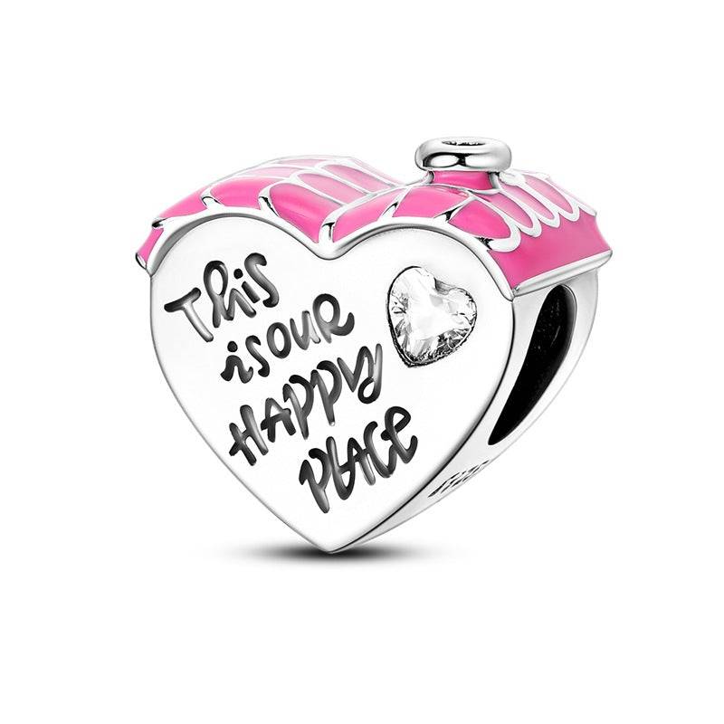 Heart-shaped charm with pink roof and 'This is our happy place' engraving. A sentimental love charm for bracelets symbolising home and joy.