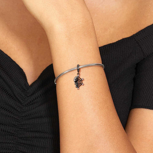 Skull Web Charm worn on a bracelet, showcasing its striking skull and web design with pink stones. Perfect for bold fashion statements.