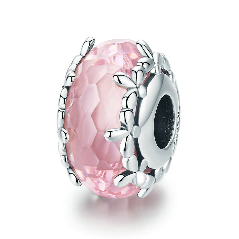 Silver charm with pink gemstone on a white background