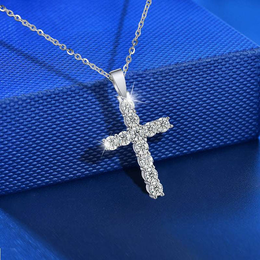 Moissanite Cross Necklace displayed on a blue textured surface, showcasing its white gold setting and sparkling moissanite stones.