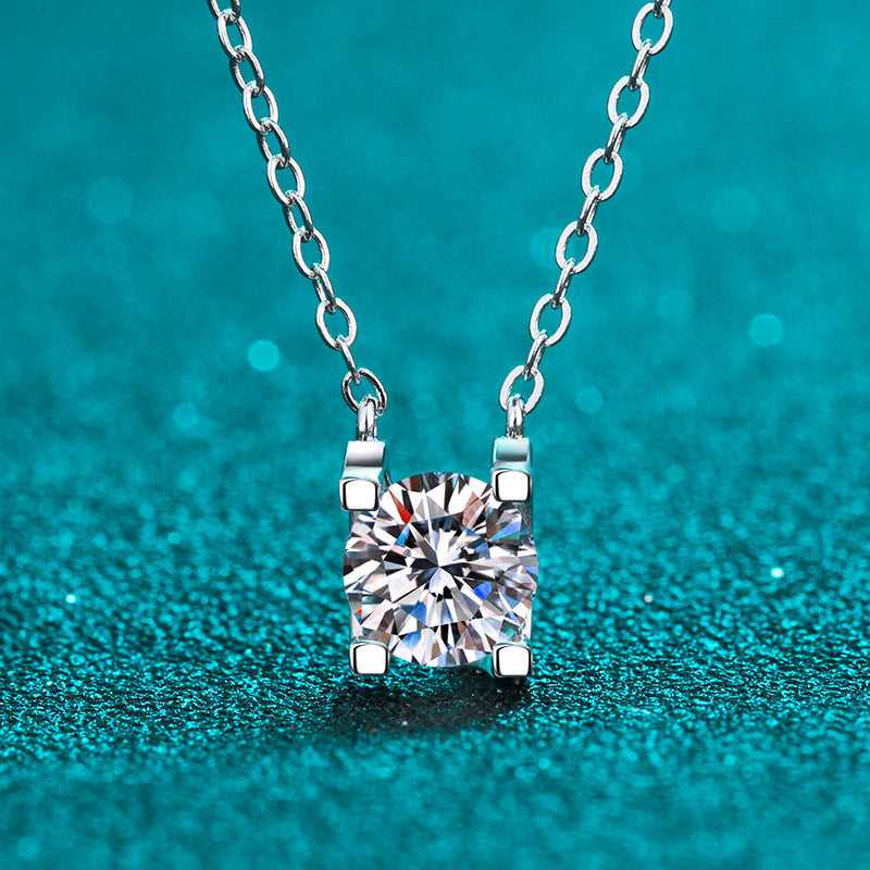Square Silver Moissanite Necklace displayed on a glittery teal surface, highlighting the clarity and sparkle of the moissanite stone in a silver setting.