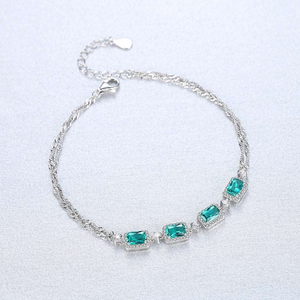 Flat lay of Baguette Cut Emerald Bracelet with four emerald stones and silver chain, perfect for adding a touch of luxury to any outfit.