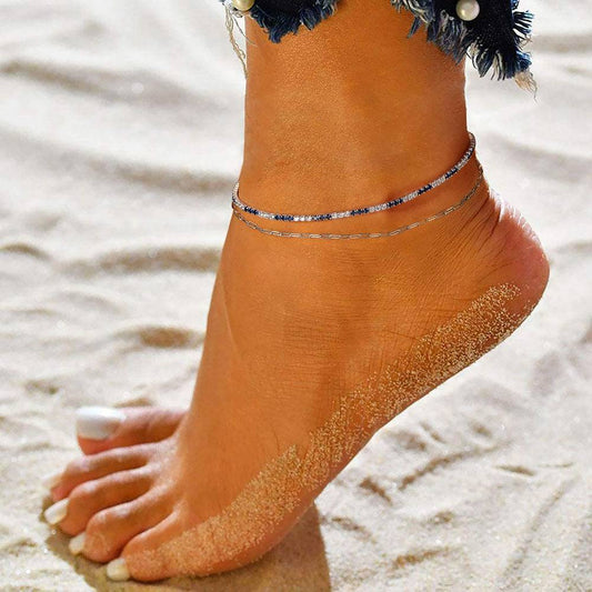 Elegant Gold/Platinum Anklet worn on a sandy beach, showcasing its delicate design and versatility for summer or beachwear fashion.
