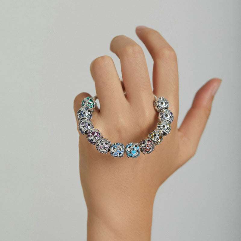 Hand wearing a bracelet with multiple Birth Month Charms, showcasing colorful stones and heart designs in 925 sterling silver.