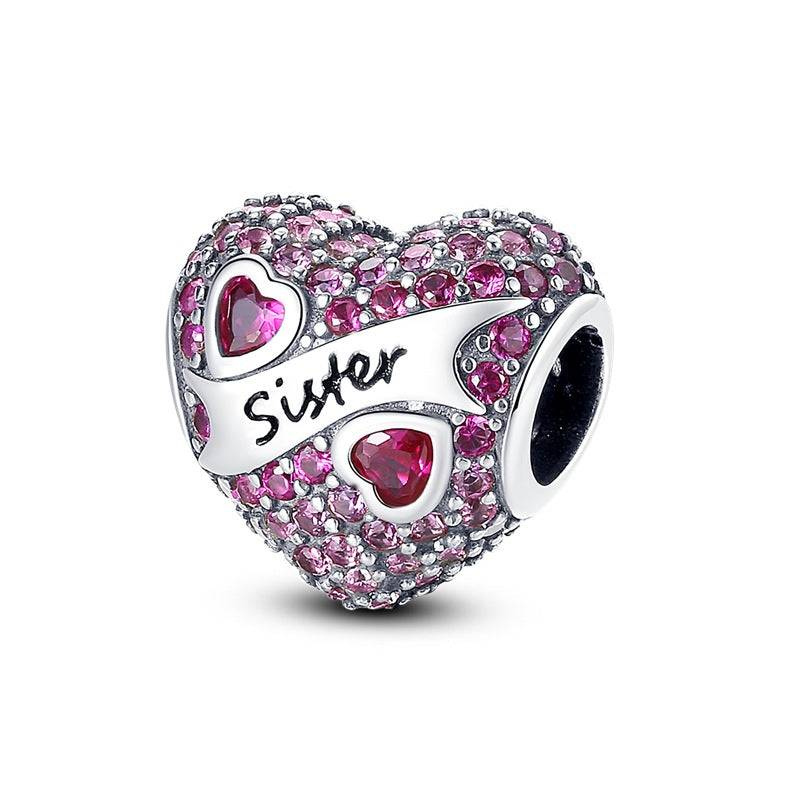 Heart charm encrusted with pink stones and 'Sister' engraving. A sparkling love charm for bracelets celebrating sisterly love and bond.
