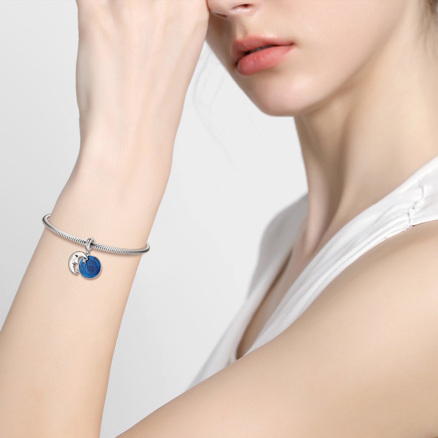Model wearing the Moonlight Charm on a silver bracelet, showcasing its elegant celestial design and vibrant blue enamel centerpiece.