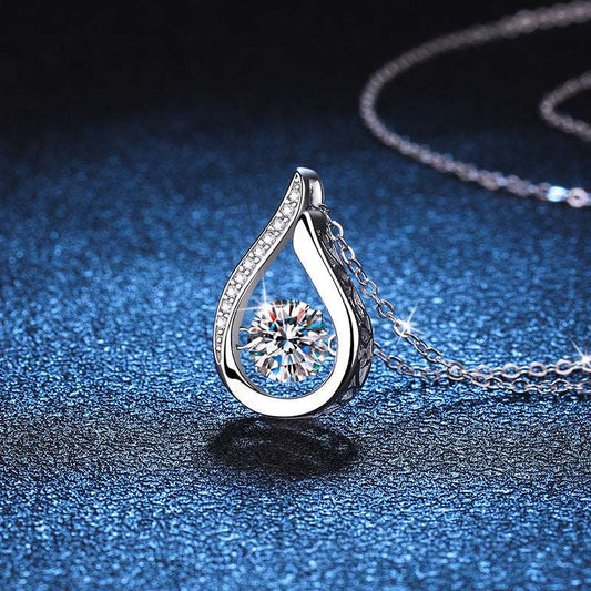 Elegant Droplet Moissanite Necklace displayed on blue textured background, showcasing its sparkling 1-carat stone and silver finish.