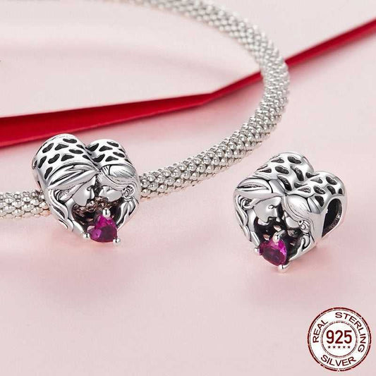 Sterling silver Mother And Daughter Charm displayed on a mesh bracelet, showcasing its heart design and pink gemstone centerpiece.