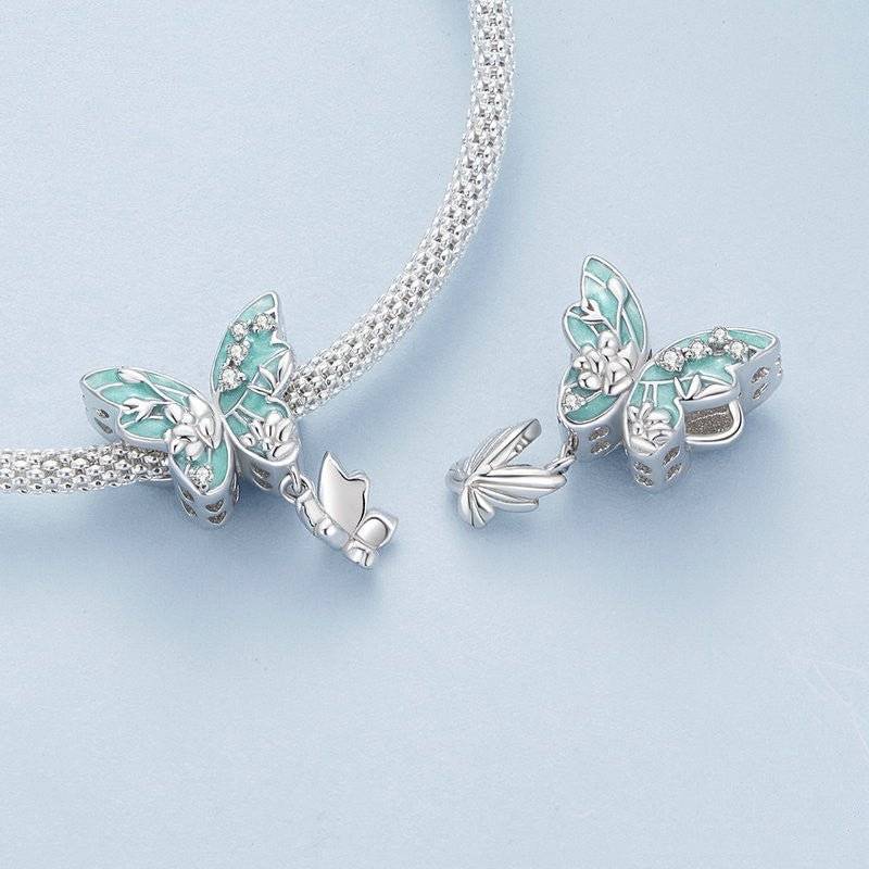 Floral Butterfly Charm featuring silver and teal enamel wings with floral accents, symbolizing nature’s beauty and transformation 🦋🌸.