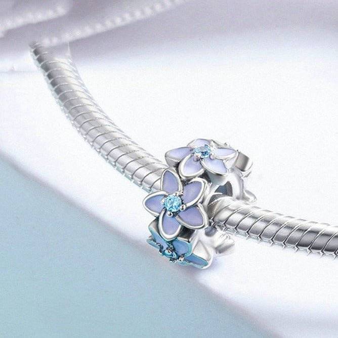 Elegant flower spacers for charm bracelets featuring pastel enamel petals and blue crystal centers, ideal jewellery accessory for personalized designs.