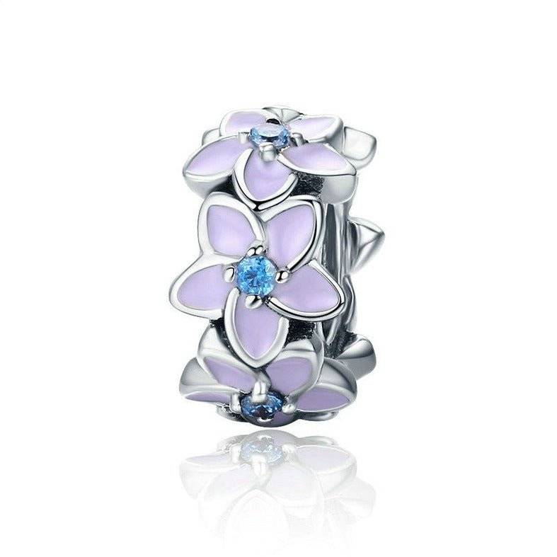 Elegant flower spacer charm with purple enamel petals and blue crystal centers, ideal for charm bracelets and stylish jewellery designs.