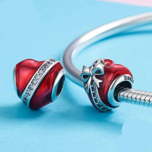 Heart Gift Charm in red enamel with silver bow and crystal accents, ideal for bracelets. A romantic jewelry piece for sharing love and joy.