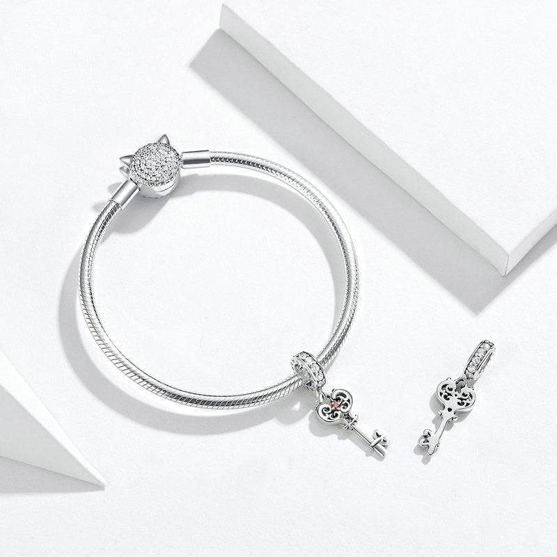 Elegant Key Charm in silver with intricate heart-shaped detailing, shown with matching bracelet. Ideal for charm bracelets or pendants.