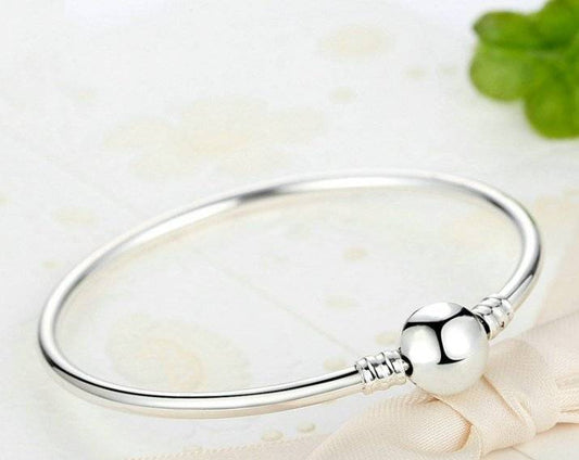Elegant silver bangle bracelet with polished round bead centerpiece, perfect for adding timeless style to any outfit or occasion.
