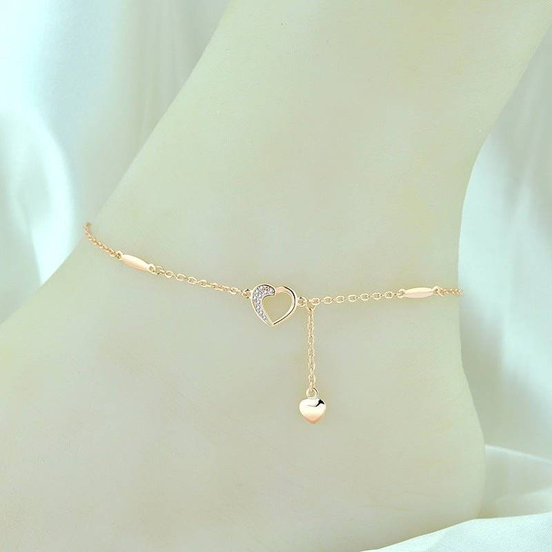Rose gold Charming Heart Anklet on ankle with a dangling heart charm and crystal-studded heart, a romantic accessory for any occasion.