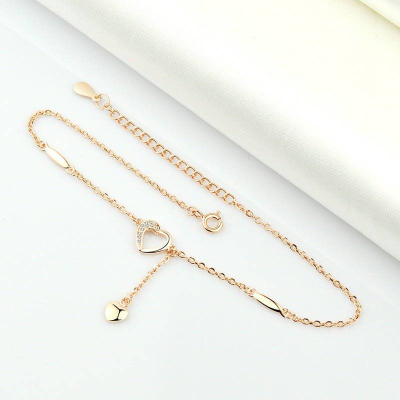 Flat-lay of rose gold Charming Heart Anklet with adjustable chain and heart details, crafted for a chic and feminine jewelry style.