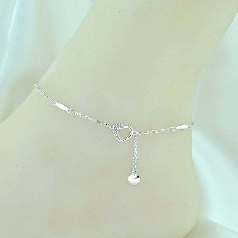 Silver Charming Heart Anklet worn on ankle, featuring a delicate heart charm and crystal detailing, perfect for casual or formal outfits.