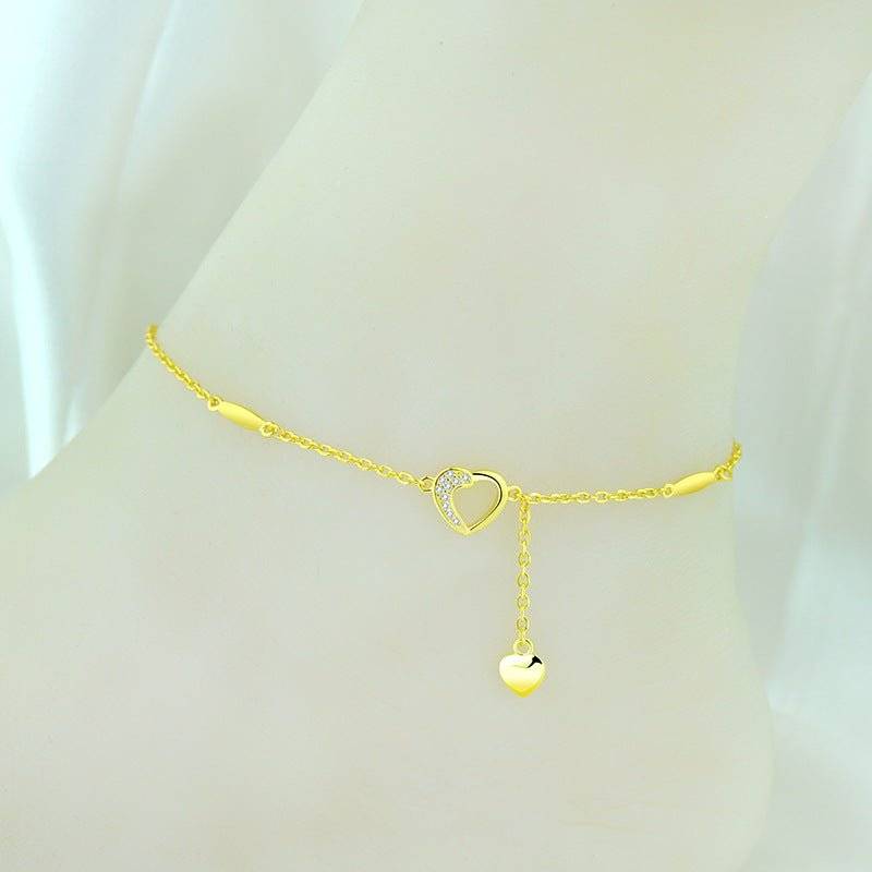 Gold Charming Heart Anklet displayed on ankle, showcasing a dainty heart drop and sparkling crystal heart centerpiece for a stylish look.