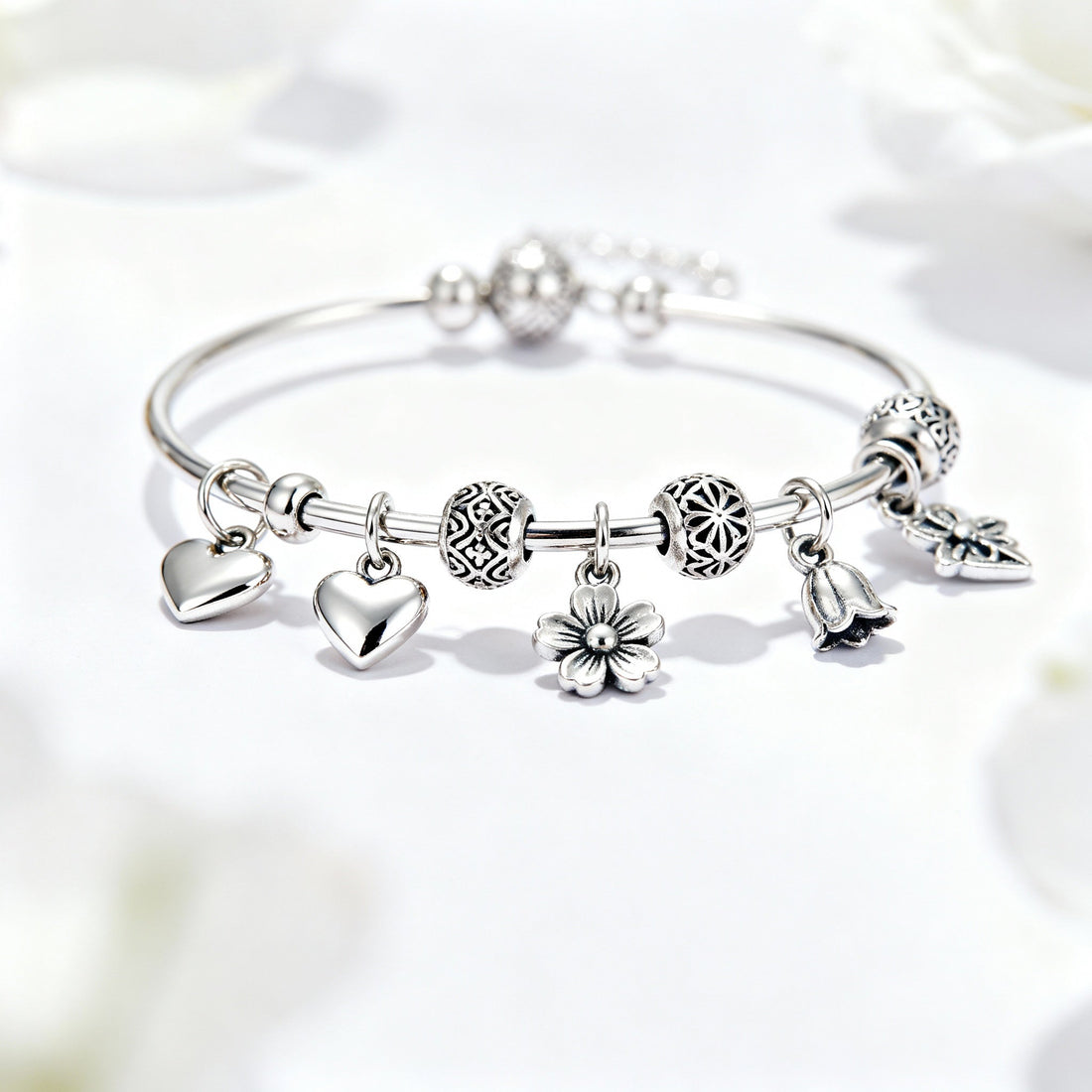 Elegant silver charm bracelet with heart, flower, and bell charms