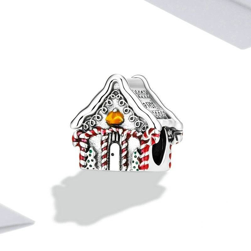 Silver gingerbread house charm with red and white details on a white background