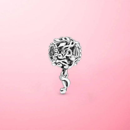 Sterling silver musical note charm with a dangling note accent, set against a soft pink background for an elegant jewelry showcase.