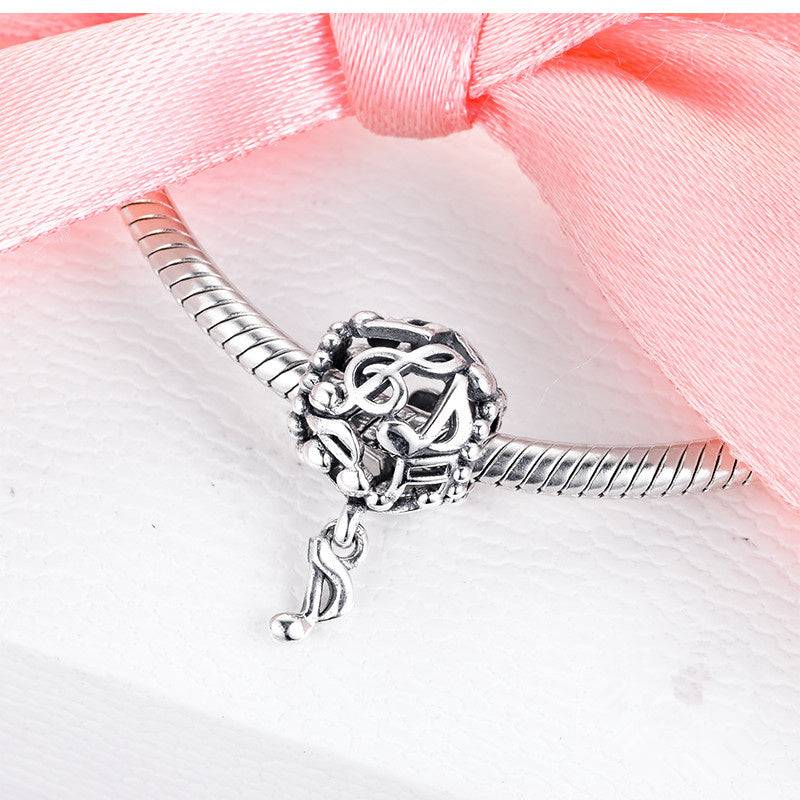 Sterling silver musical note charm attached to a bracelet, beautifully displayed with a pink ribbon for a stylish gift presentation.