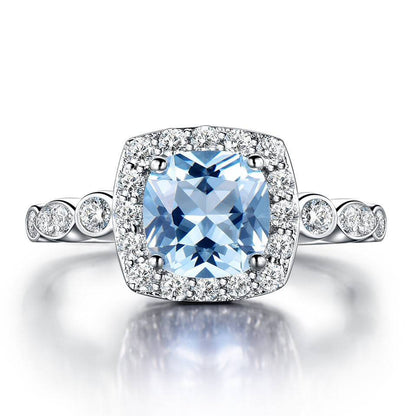 Sterling Silver Blue Topaz Ring with cushion-cut center stone and halo of cubic zirconia, crafted in 925 silver for lasting brilliance.
