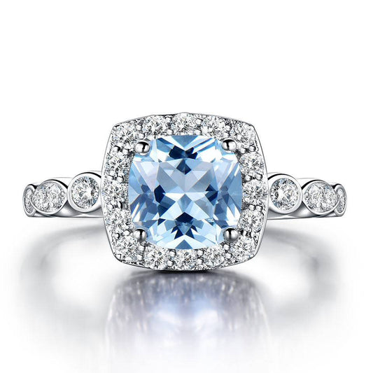 Sterling Silver Blue Topaz Ring with cushion-cut center stone and halo of cubic zirconia, crafted in 925 silver for lasting brilliance.