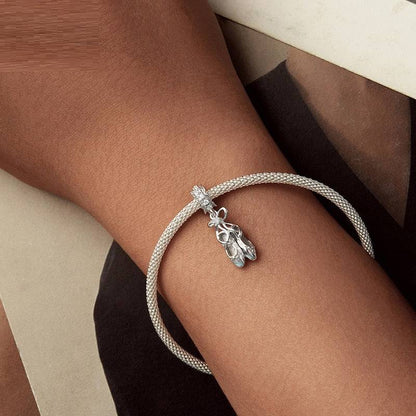 Ballet Shoes Charm in sterling silver styled on a bracelet worn on a wrist. A graceful addition to any jewelry collection.