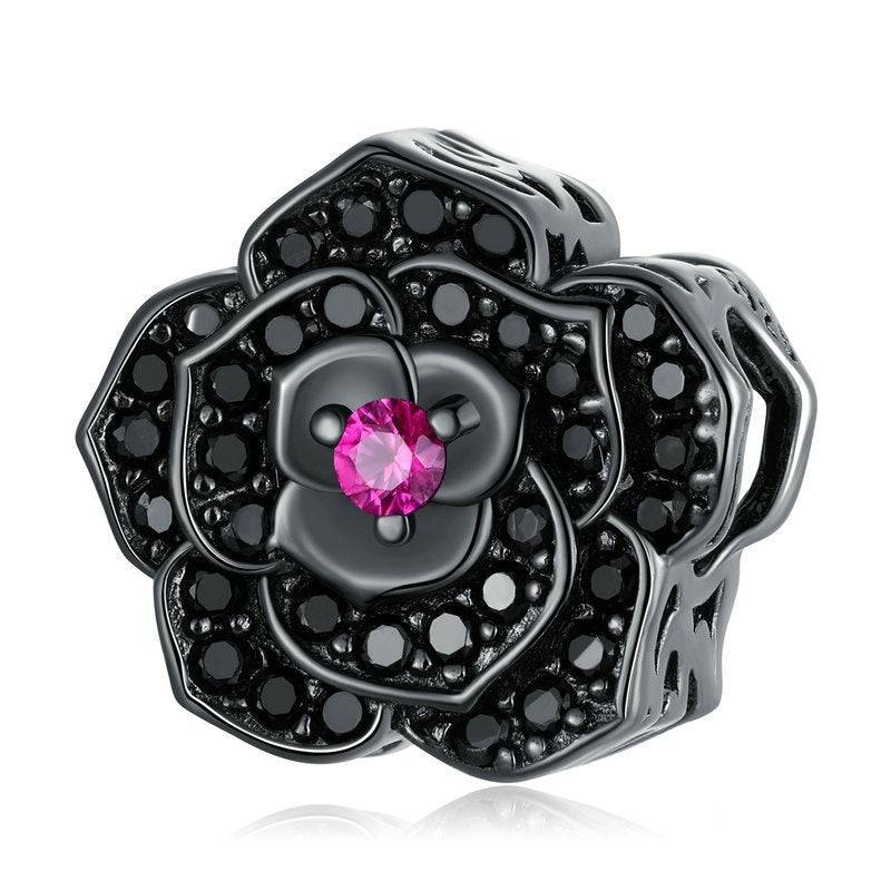 Black flower-shaped jewelry with a pink gemstone on a white background