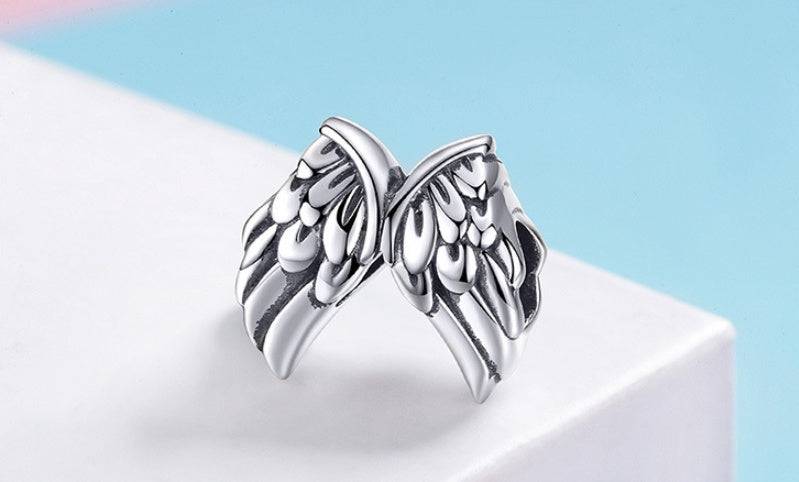 Elegant Guardian Wings Charm displayed on a pastel background, crafted in sterling silver. A symbolic accessory representing strength and guidance.