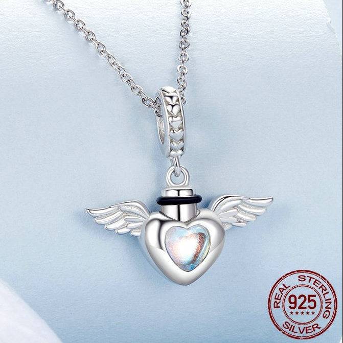 Silver heart-shaped pendant with wings on a chain, featuring 'Real Sterling Silver' stamp.