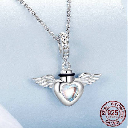Silver heart-shaped pendant with wings on a chain, featuring 'Real Sterling Silver' stamp.