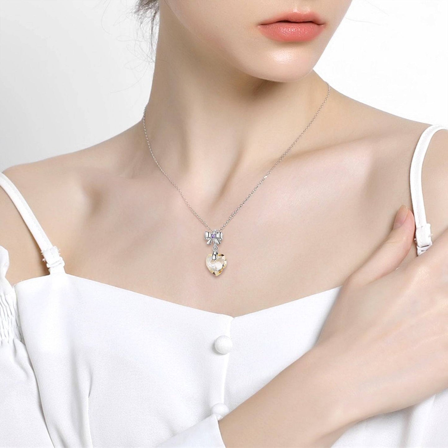 Golden Crystal Charm worn as a necklace, highlighting its heart-shaped gemstone and silver bow accent. A stunning jewelry piece.