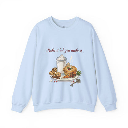 Women’s Sweatshirt - “Bake it ‘til you make it” in light blue with festive pie, cookies, and whipped drink graphic, perfect for cozy winter fashion.