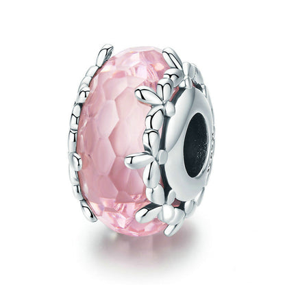 Silver charm with pink gemstone on a white background