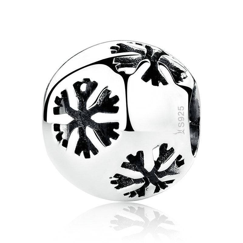 Silver charm with snowflake design on a white background