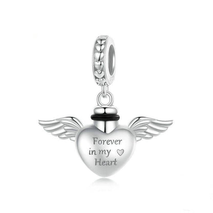 Silver heart-shaped pendant with wings and 'Forever in my Heart' engraving on a white background.