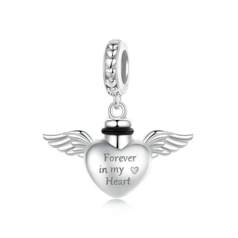 Silver heart-shaped pendant with wings and 'Forever in my Heart' engraving on a white background.