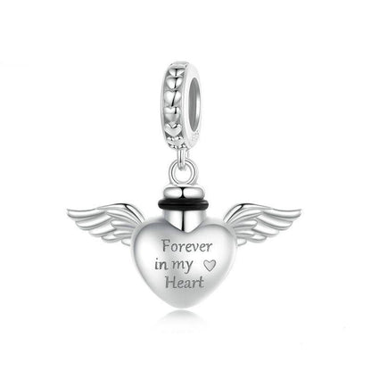 Silver heart-shaped pendant with wings and 'Forever in my Heart' engraving on a white background.