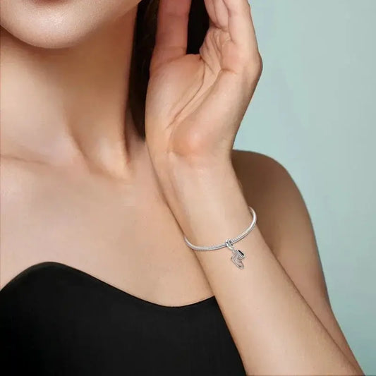 Snow Boot Charm - Winter Accessory | Symbol of Warmth, featured on a silver bracelet worn by a woman in a black strapless top.