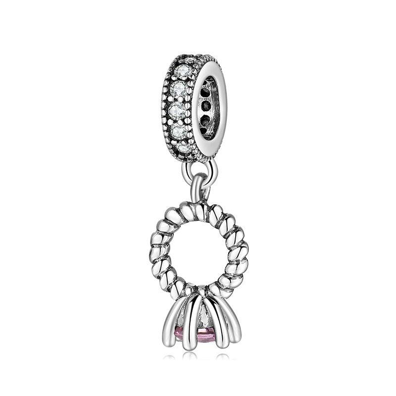 Silver charm with circular design and pink accent