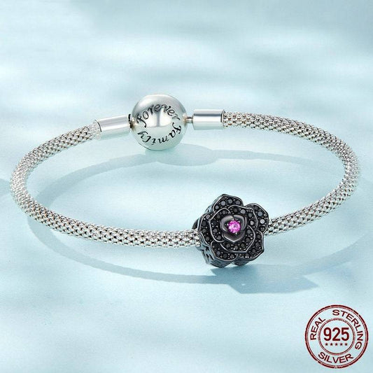 Gothic Charm: Embrace Dark Elegance - Black Rose charm on sterling silver bracelet with intricate mesh design and pink gemstone center.