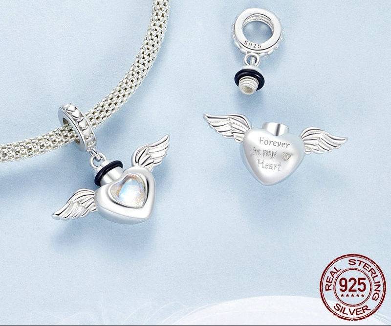 Silver heart-shaped pendant with wings and 'Forever in my Heart' text on a light blue background.