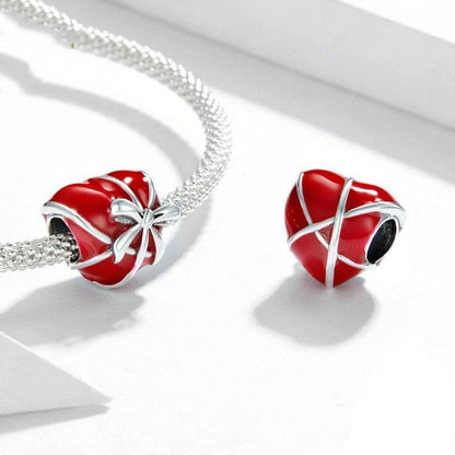 Two red heart charms with silver bow on bracelet